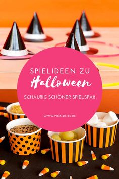 halloween party food with candy and candies in striped paper cups on a black table