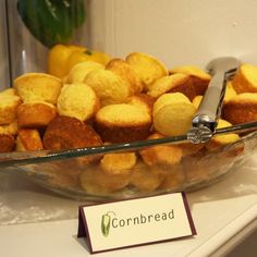 a glass bowl filled with cornbread muffins next to a sign that says cornbread