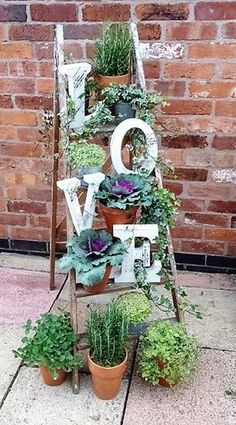 an old ladder is filled with potted plants and the word love spelled out on it