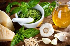 ingredients for pesto sauce on wooden cutting board with garlic, basil and sunflower oil