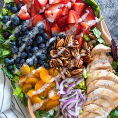 a salad with chicken, fruit and pecans on it