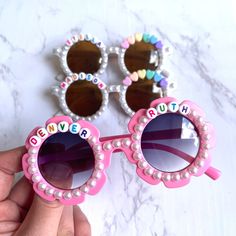 a pair of pink sunglasses with the words denver written on them and pearls attached to it