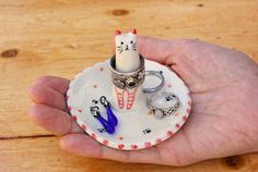 a person's hand holding a small plate with scissors and a cat ring holder