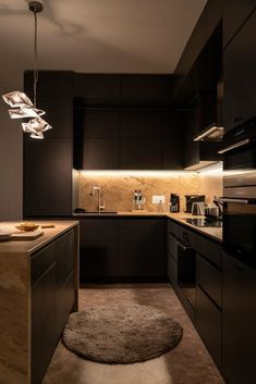 a modern kitchen with black cabinets and marble counter tops is lit by pendant lights that hang from the ceiling