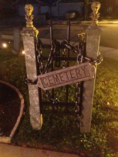 a cemetery sign is chained to chains and stands in front of a gate with the word cemetery written on it