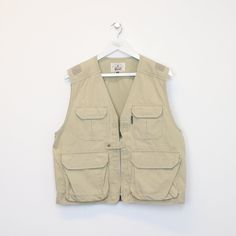 "SKU - DM6220 Vintage Taras Boulba vest in Beige. Best fits M DETAILS ▫️ Zip up ▫️ Pockets   👕 Fits like a ~ M ▫️ Label states ~ L ▫️ Pit to Pit ~ 22\" ▫️ Length ~ 24\" ▫️ Pit to Cuff ~ N/A   👇 If any defect is found and it is not included in the provided photos, it will be listed below. ▫️     🧺 All items are professionally washed and ironed before photos are taken and then sold.    ✅ If the item is listed, it is available   ❌ Disclaimer: Like all vintage items they may have slight imperfections and defects that can go unseen while listing. However, each item is washed before listing and all discovered defects will be noted above." Summer Khaki Vest With Pockets, Utility Sleeveless Tops With Pockets, Sleeveless Utility Top With Pockets, Utility Sleeveless Outdoor Vest, Utility Cotton Sleeveless Tops, Utility Sleeveless Vest For Summer, Summer Utility Sleeveless Vest, Adventure Sleeveless Vest With Pockets, Sleeveless Vest With Pockets For Adventure