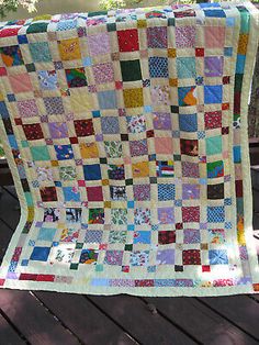 a quilt on a wooden deck with trees in the background