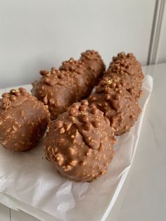 three chocolate donuts are sitting on a napkin