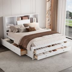 a white bed with drawers underneath it in a bedroom next to a large sliding glass door