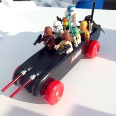 star wars action figures are riding in a toy race car with red wheels on a white table