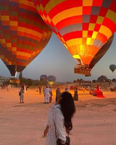 several hot air balloons are being inflated in the sky at dusk, with people watching