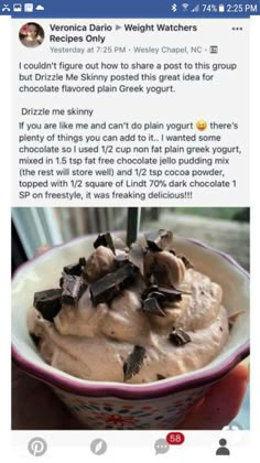 a bowl filled with chocolate ice cream on top of a wooden table next to a window