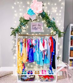 a white shelf filled with lots of colorful clothes and shoes next to a wall covered in lights