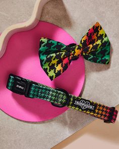 two colorful bow ties sitting on top of a pink plate next to a wooden spoon