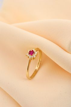 a close up view of a gold ring with a red stone