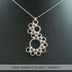 a silver necklace on a black surface with the words rain studio at any c sanders