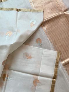 An exquisite pure 100% silk organza/kora benarasi saree in off white with copper & silver alfi buta (floral motif) woven throughout the six yards, along with a sleek golden border on either side. This saree is very stylish and classy, especially because of its simplicity and grace. The alfi (technique in Benaras weaving using two colored yarns) buta looks so stunning with the silver and copper zari as it keeps alternating with each motif. The pallu has a solid copper zari weaving. The fabric Elegant Festive Saree With Kora Detailing, Elegant Saree With Kora Detailing For Festive Occasions, Elegant Saree With Kora For Festive Occasions, Elegant Kora Saree For Festive Occasions, Elegant Wedding Saree With Kora Detailing, Elegant Dupatta With Kora In Traditional Drape, Elegant Kora Dupatta In Traditional Drape, White Silk Saree With Zari Weaving, White Silk Saree With Pallu