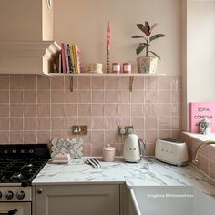 a kitchen with pink tiles and marble counter tops, white appliances and an open shelf above the stove