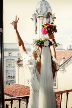 a woman in a wedding dress is standing on a balcony with her arms raised up