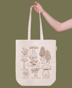 a hand holding a tote bag with mushrooms on it