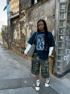 a young man with dreadlocks standing in front of an old building on the street