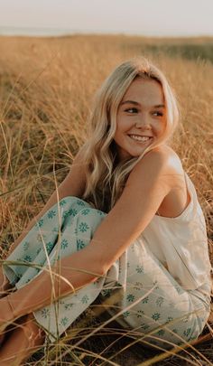 a woman sitting in the grass smiling at the camera