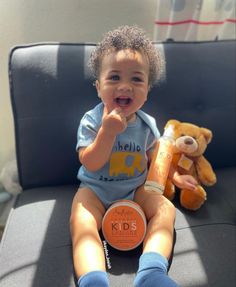 a baby sitting on a couch with a stuffed bear