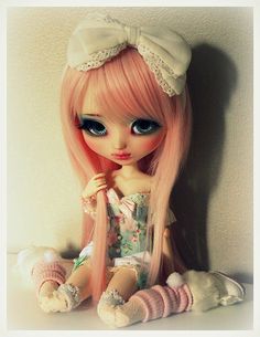 a doll with pink hair sitting on the floor