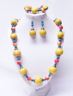 "Large Round Yellow Wood w/Red/Yellow Acrylic Bead Necklace/Bracelet/Earrings Set  This necklace set is made with large round yellow wood beads, 12mm round red and white acrylic beads, 6/7mm turquoise wood beads and silver plated spacer beads strung on flexible beading wire. It is 26\" in length and it fastens with silver plated lobster clasp. It comes with bracelet and earrings that hang from silver plated fish hook ear wires. Necklace Length: 26\" Earrings Length: 2 ½\" (including ear wire)  B Adjustable Round Multicolor Jewelry Sets, Yellow Polished Round Beads Jewelry, Adjustable Yellow Jewelry Sets For Gift, Adjustable Yellow Polished Beads, Adjustable Yellow Polished Beaded Necklaces, Yellow Wooden Beads For Jewelry Making, Yellow Round Beads For Jewelry Making, Handmade Yellow Jewelry With Round Beads, Handmade Yellow Round Beaded Jewelry