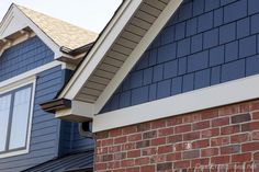 two houses with blue sidings and white trim on the roof, one has a red brick chimney