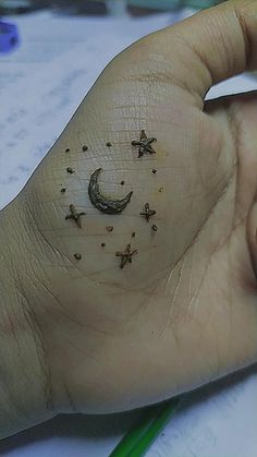 a person's hand with small stars and moon tattoos on it