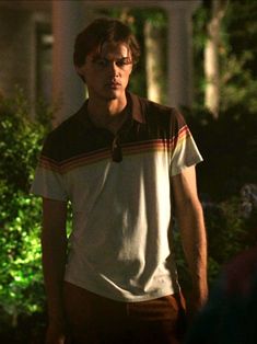 a young man standing in front of a house at night with his eyes closed and one hand on his hip