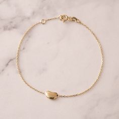 Elevate everyday elegance with our Little Bean Charm Bracelet in 14k/18k SOLID Gold. A trendy must-have, perfect for best friend gifts, baby showers, and more.  Embrace simplicity, celebrate life. Your ultimate charm adventure awaits! Material: Solid Gold, real gold (not gold filled or no gold plated) Available Gold Karat: 14K Gold (585), 18K Gold (750) Available Gold Color: Yellow (gold), Rose, White Bean height: 0.55 cm Bean width: 0.80 cm Bracelet Length: Available Between 6.0 - 8.0 Inches 6.0 inch bracelet (Little Girl) 6.5 inch bracelet is adjustable 6.0 inc (Teen - Petite) 7.0 inch bracelet is adjustable 6.5 inc (Adult - Small) 7.5 inch bracelet is adjustable 7.0 inc (Adult - Medium) 8.0 inch bracelet is adjustable 7.5 inc (Adult - Large) 8.5 inch bracelet is adjustable 8.0 inc (Adul Dainty 14k Yellow Gold Heart Bracelet, Minimalist Yellow Gold Chain Bracelet For Anniversary, Formal 14k Yellow Gold Heart Bracelet, Minimalist Yellow Gold Heart Bracelet With Delicate Chain, Delicate 14k Yellow Gold Bracelets, Elegant 14k Gold Heart Bracelet, Elegant 14k Gold Round Heart Bracelet, Dainty Yellow Gold Bracelets With Polished Finish, Minimalist Yellow Gold Oyster Bracelet