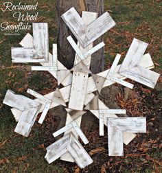 a snowflake made out of wooden planks sitting in the grass next to a tree