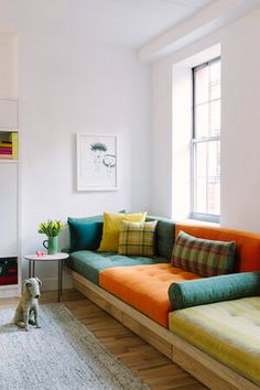 a living room filled with furniture and a dog sitting on the floor next to it