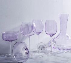 several wine glasses are lined up next to each other on a counter top, with one empty glass in the middle