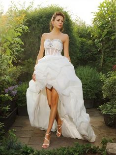 a woman in a white dress walking through some bushes