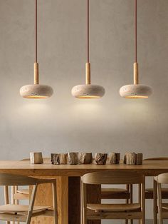 three lights hanging over a wooden table with four chairs and two tables in front of it