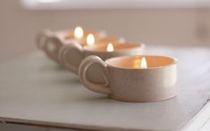 some white cups with candles in them sitting on a table