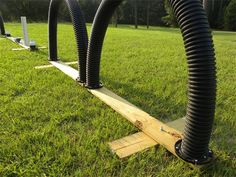 several black hoses connected to wooden posts in the grass