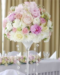 a tall vase filled with pink and white flowers on top of a dining room table