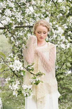 a woman standing in front of a tree with white flowers