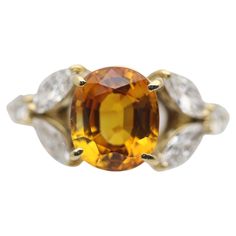 A sweet and stylish ring featuring a bright vivid orange sapphire weighing 3.58 carats. It has a rich orange color and a lovely oval shape. Complementing the sapphire are 0.81 carats of large marquise and round brilliant-cut diamonds set in a floral style on the sides of the ring. Made in 18k yellow gold and ready to be worn. Ring Size 6.25 Weight: 4.2 grams Engangement Ring, Orange Sapphire Ring, Yellow Sapphire Ring Engagement, Estate Diamond Jewelry, Garnet And Diamond Ring, Platinum Diamond Engagement Rings, Gold Cocktail Ring, Orange Sapphire, Platinum Engagement Rings