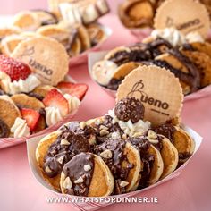 several desserts are arranged in pink boxes on a table with strawberries and other pastries