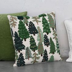 two pillows sitting next to each other on top of a floor covered in green and white christmas trees