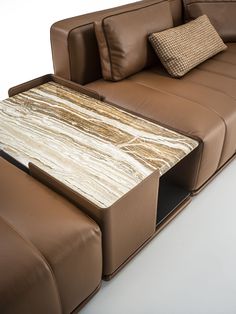 a brown leather couch with a marble coffee table in the middle on top of it