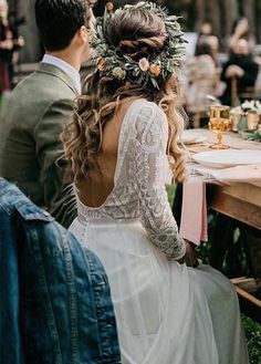 a man and woman sitting at a table with flowers in their hair