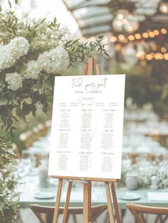 an easel with seating cards and flowers on it