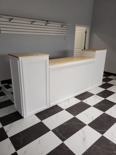 a white and black checkered floor with two counter tops on each side in an empty room