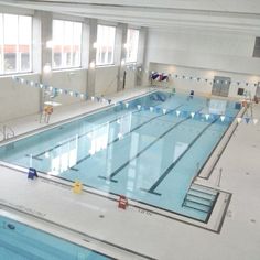 an indoor swimming pool with blue and white flags hanging from the ceiling next to windows